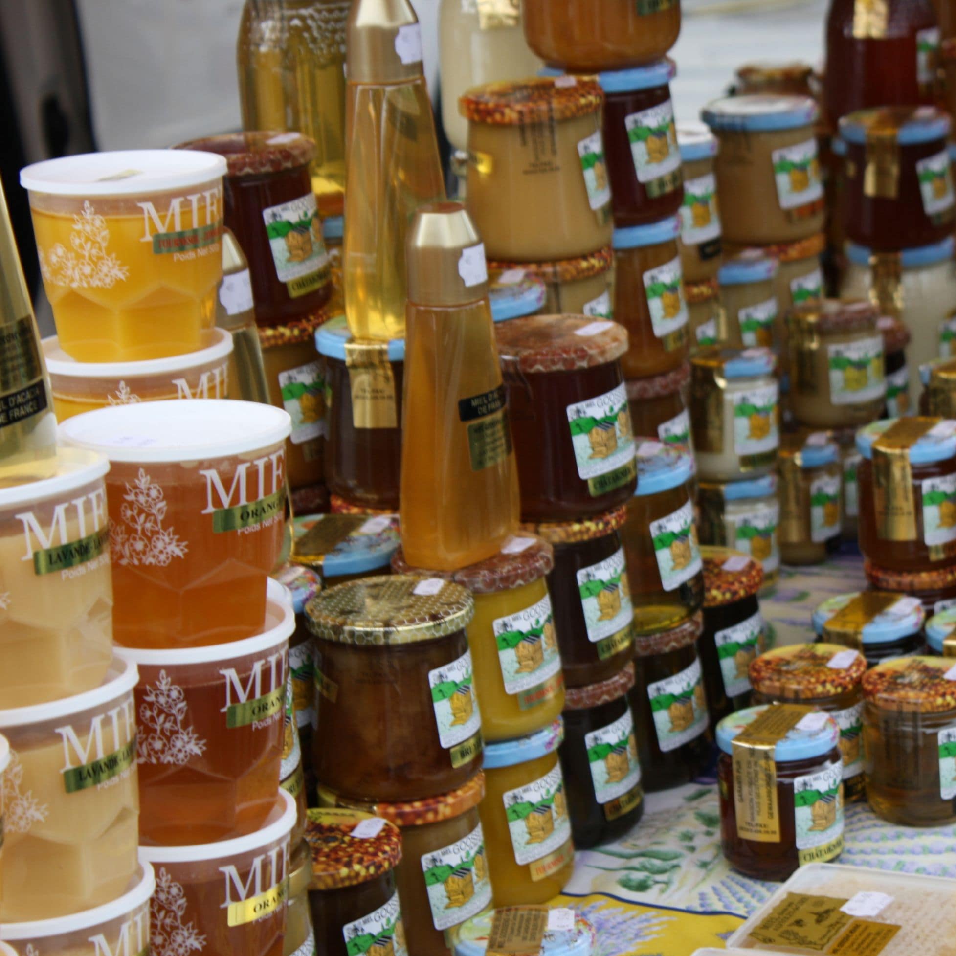 Multiples pots de miels en plastique et en verre avec étiquettes adhésive similaire à celles produites sur le service d'impression Yetiq.pro
